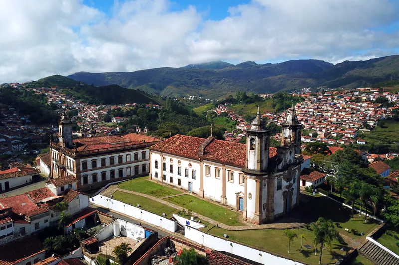 Igreja e casario do centro histórico de Ouro Preto, com a serra ao fundo.
